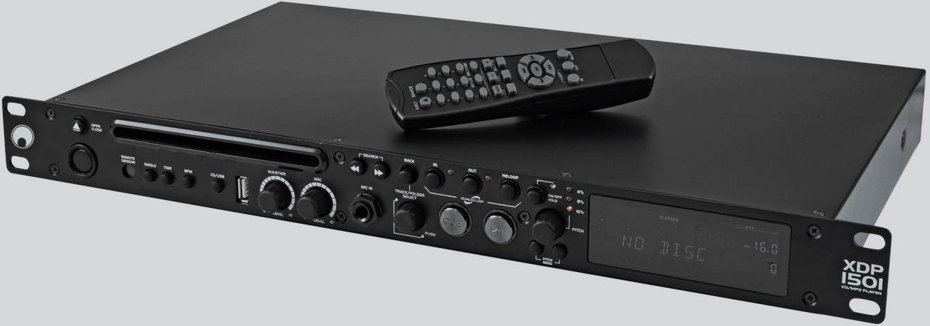 Un appareil audio noir avec des boutons et un écran. Une télécommande repose dessus. Sur la gauche, différents ports sont visibles.