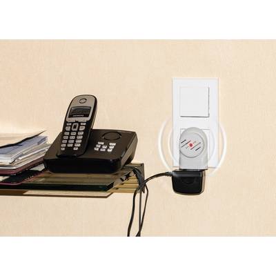 Système européen de surveillance des détecteurs de fumée affichant un téléphone avec station de base à côté d'une prise électrique avec des appareils branchés.