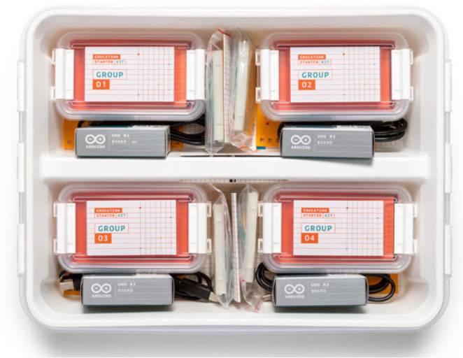 Quatre boîtes transparentes portant les inscriptions 'Groupe 01' à 'Groupe 04', contenant des composants électroniques dans un organisateur.