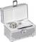 Valise argentée ouverte, contenant un grand poids métallique et des accessoires plus petits sur un fond de mousse blanche.