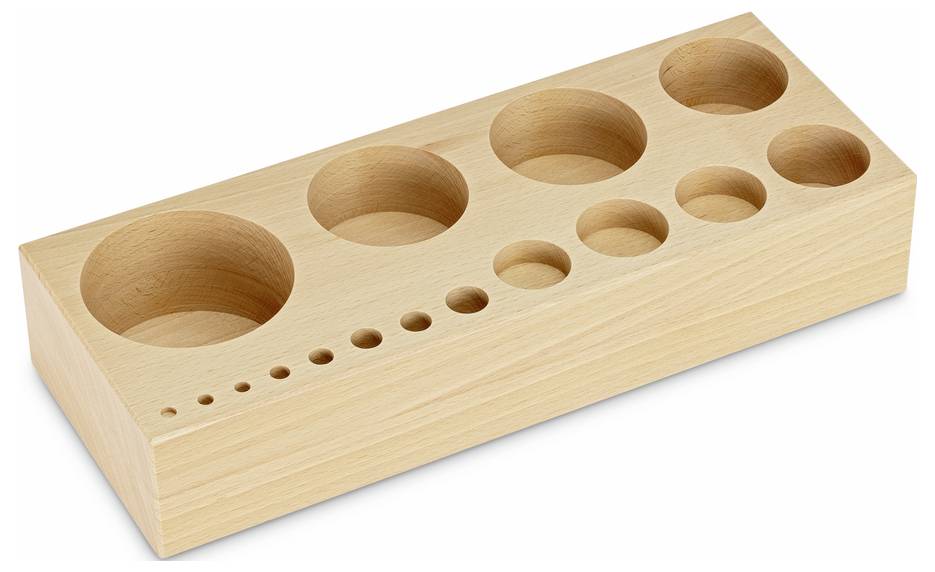 Bloc de bois percé de trous de différentes tailles, probablement utilisé comme instrument de mesure ou pour ranger de petits objets.