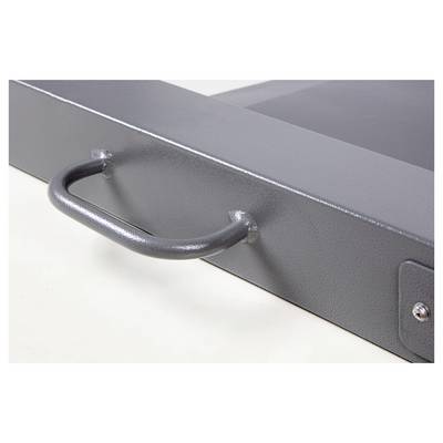 Poignée métallique sur un objet rectangulaire gris, probablement une boîte à outils ou un tiroir. La surface est légèrement texturée.