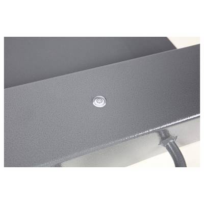 Une table en métal grise avec un petit bouton circulaire au centre. Un câble descend du côté inférieur droit de la table.