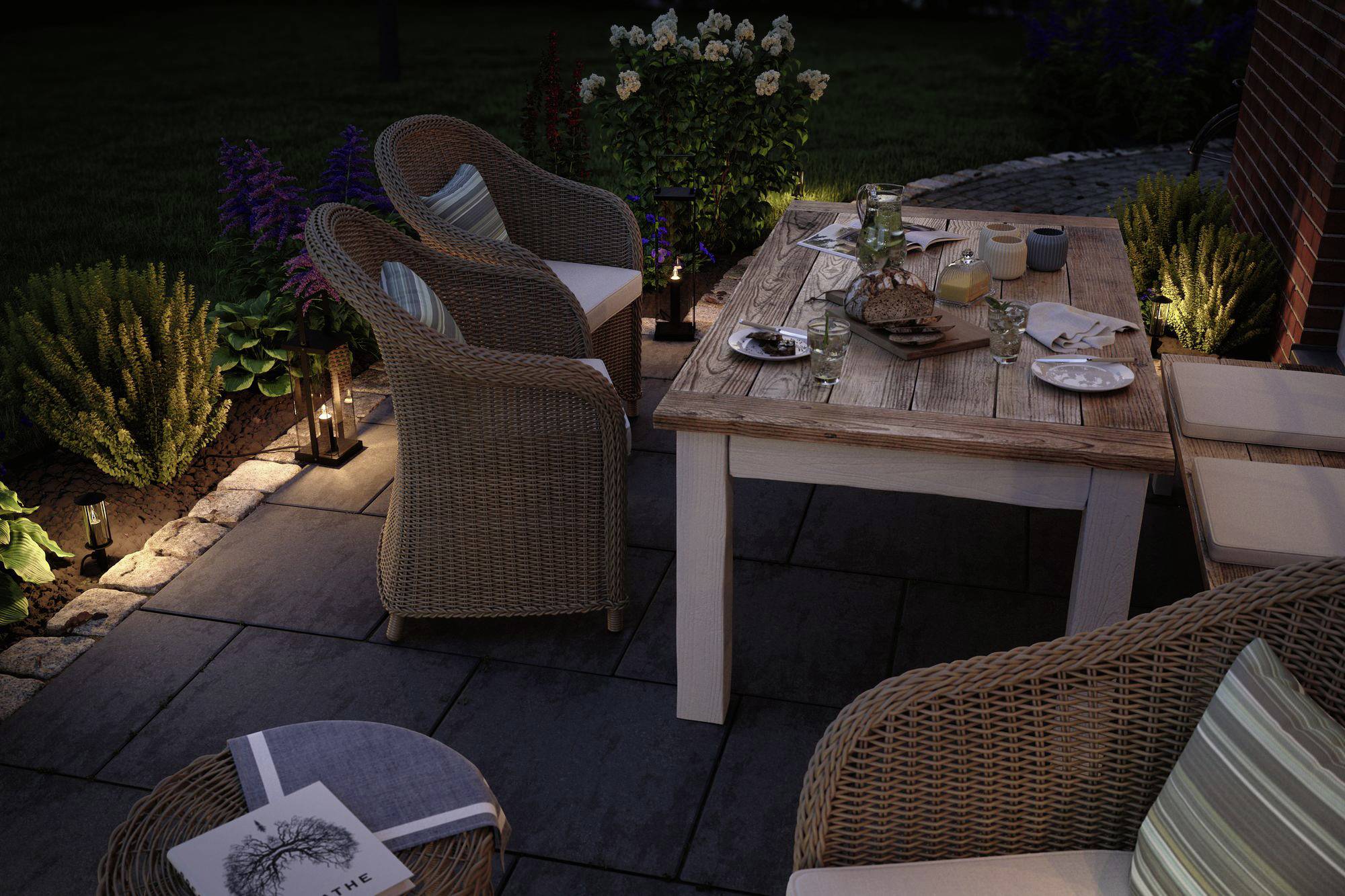 Une table de jardin éclairée avec des chaises. Sur la table, des verres et des assiettes sont disposés. Tout autour, on trouve des plantes et un éclairage.