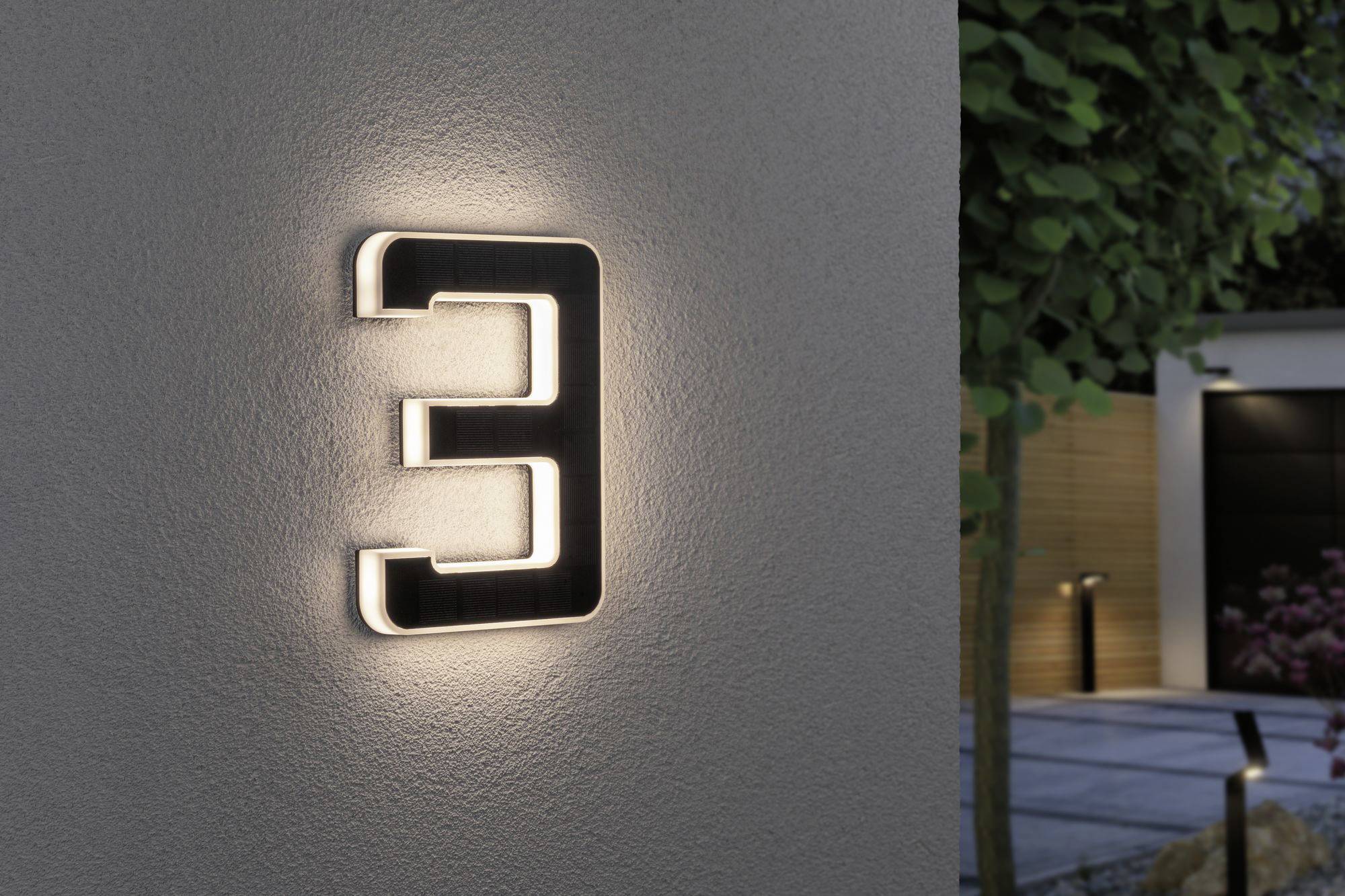 Numéro de maison lumineux 3 sur un mur, entouré de plantes en arrière-plan ; design moderne et élégant pour une meilleure visibilité.