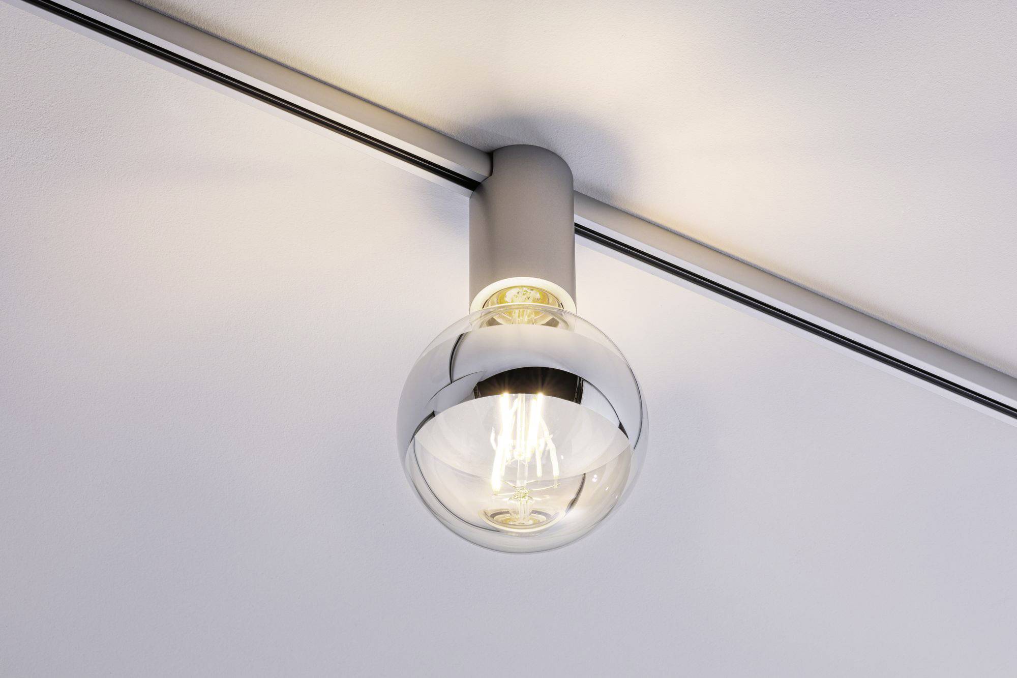 Ampoule montée dans un support moderne au plafond, brillant intensément et émettant une lumière chaude et claire.