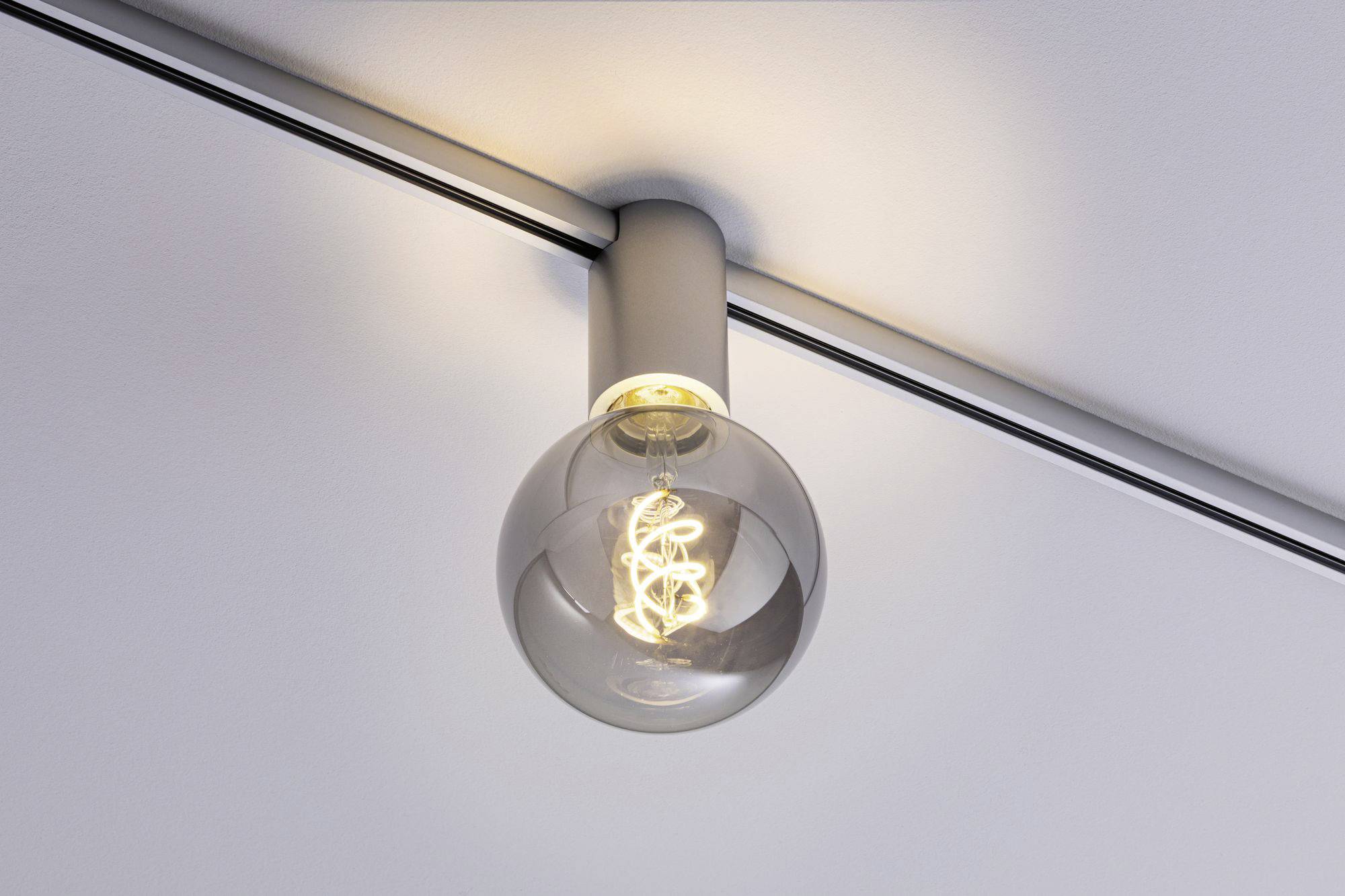 Une unique ampoule à filament décoratif, montée au plafond, illumine doucement la pièce.