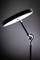 Lampadaire avec abat-jour rond blanc et socle noir, dans un langage de design moderne, présenté dans un espace sobrement éclairé.