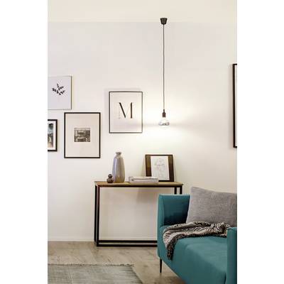 Un salon moderne avec un canapé turquoise sur lequel est posée une couverture grise. Des cadres photo sont accrochés au mur et une lampe est allumée.