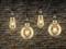 Quatre ampoules suspendues devant un mur de briques, illuminant l'espace d'une lueur chaleureuse et créant une atmosphère cosy.