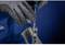 'Gros plan d'une personne en vêtements de travail bleus, travaillant avec des gants et un tournevis sur une pièce métallique.'