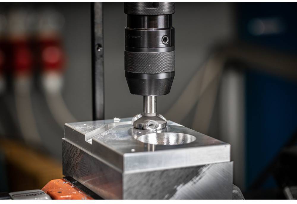 Une machine-outil fraise avec précision un motif circulaire dans un bloc de métal, entourée d'équipements industriels.