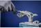 Une personne portant des gants travaille avec un outil sur une pièce métallique complexe fabriquée par impression 3D.