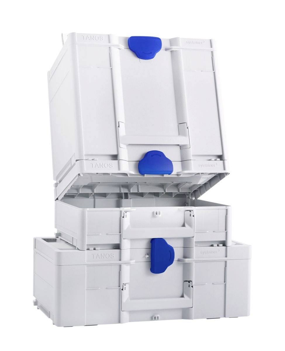 Trois boîtes de rangement blanches avec des loquets bleus sont empilées. La boîte du dessus est légèrement ouverte, révélant sa conception à emboîtement pour l'empilage.