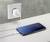 Un smartphone est posé sur une table et est connecté à une prise électrique via un câble de charge. L'écran affiche l'heure 10:21.