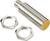 Un capteur de proximité cylindrique en métal avec un embout jaune, accompagné de deux écrous métalliques pour la fixation.