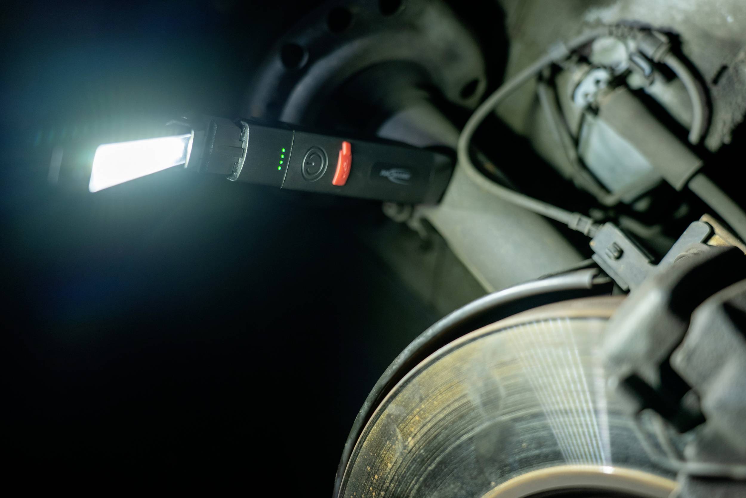 Un stylo d'inspection lumineux à côté d'un disque de frein d'un véhicule peut indiquer une usure ou un contrôle.