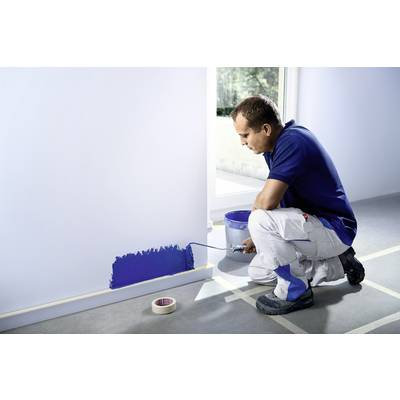 Un homme applique de la peinture bleue sur un mur à l'aide d'un rouleau. Au sol, du ruban de masquage et un seau de peinture sont posés.