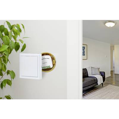 Un salon avec un mur ouvert révélant un tableau électrique dissimulé. Un canapé gris avec une couverture est visible.