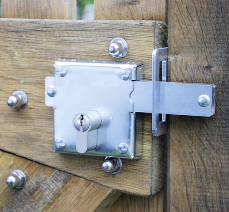 Serrure métallique avec cylindre montée sur un portail en bois, fermée.