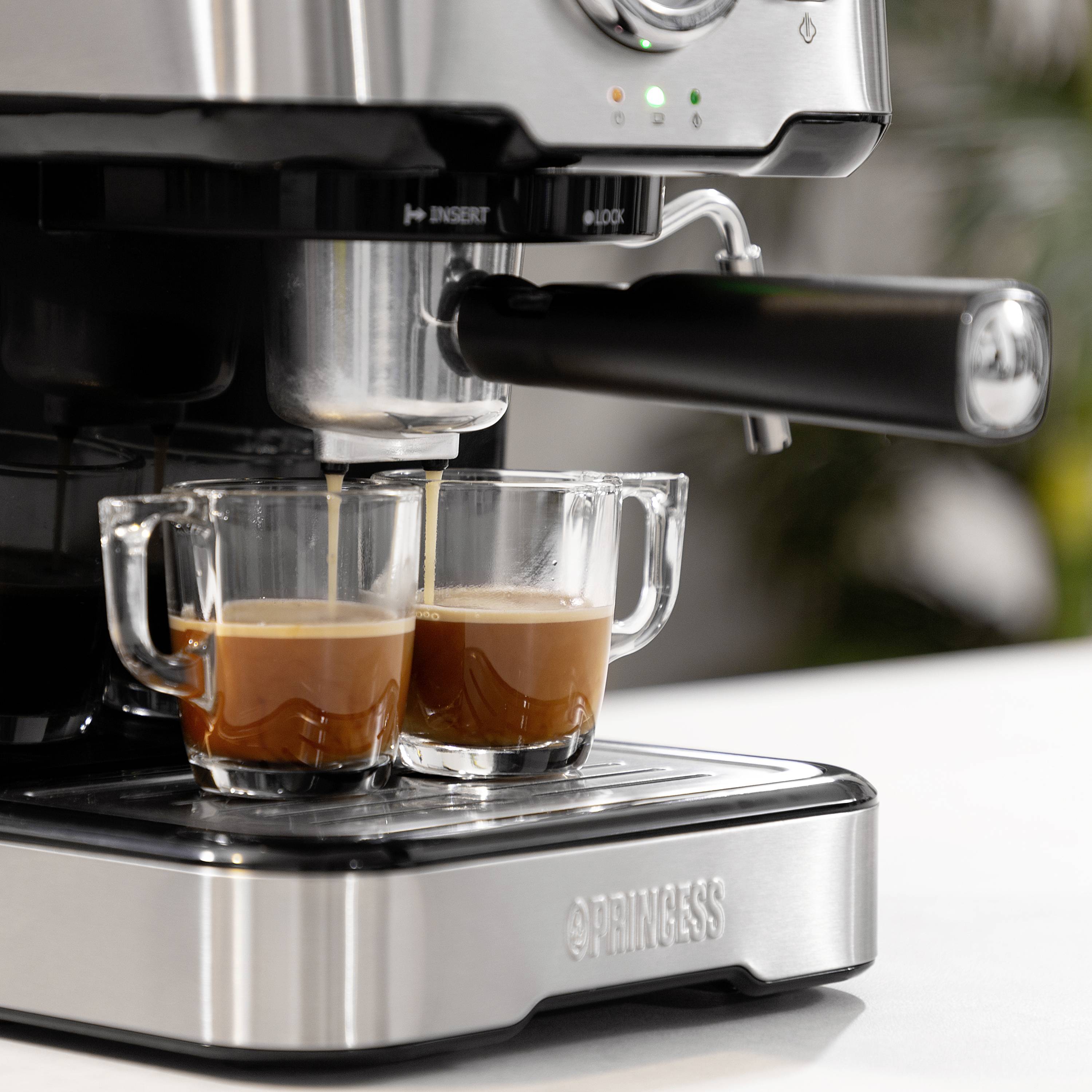 Machine à espresso préparant deux espressos simultanément dans des tasses transparentes. Design métallique, appareil de cuisine moderne en action.