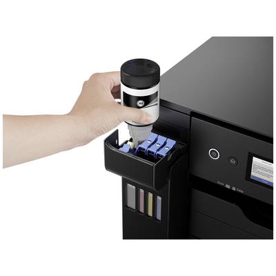 Une main remplit un imprimante avec de l'encre provenant d'une bouteille. L'imprimante montre plusieurs compartiments à encre.
