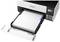 Un imprimante Epson avec un bac à papier ouvert, montrant des réservoirs d'encre couleur sur le côté droit, prêt à imprimer.