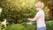 Une personne dans le jardin taille une haie avec un taille-haie électrique. Des lunettes de sécurité et des gants sont portés.