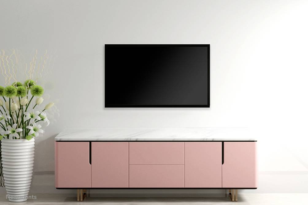 Un espace moderne avec un buffet rose et un grand téléviseur à écran plat accroché au mur. À côté se trouve un vase blanc avec des fleurs.