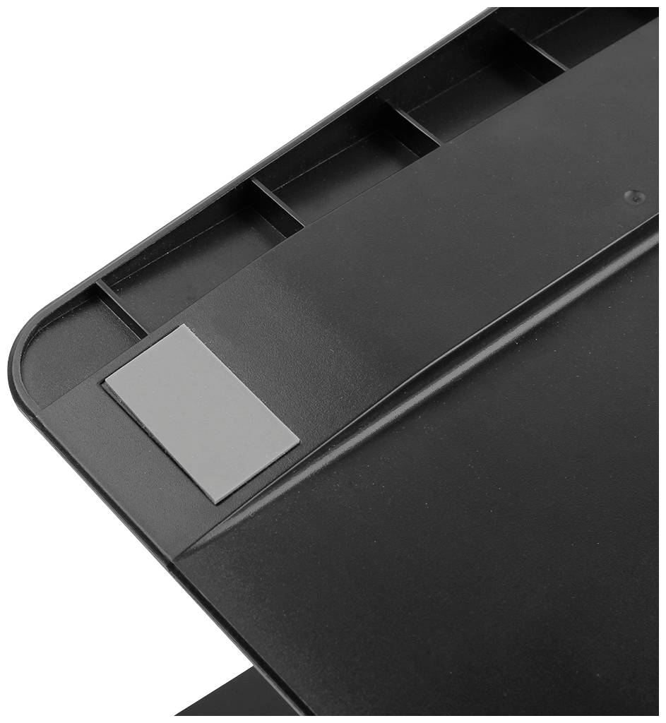 Surface en plastique noir avec un coin en caoutchouc gris ; possiblement une partie d'un couvercle de table ou d'appareil.