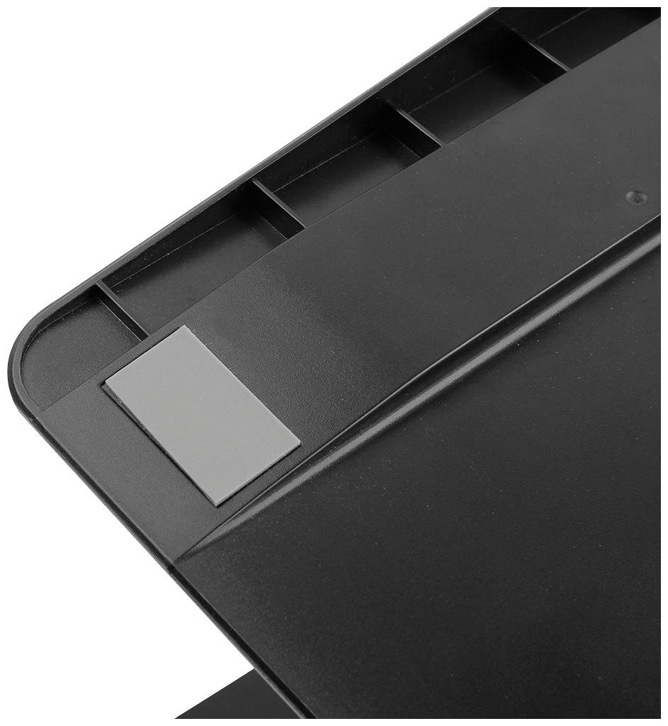 Surface en plastique noir avec un coin en caoutchouc gris ; possiblement une partie d'un couvercle de table ou d'appareil.