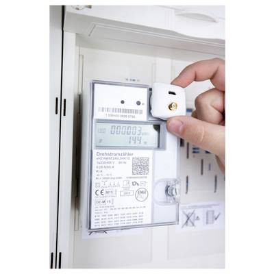 Une main plaçant un petit capteur sur un compteur électrique affichant « 000003 » kWh et « 144 » watts, indiquant la surveillance de la consommation d'énergie.