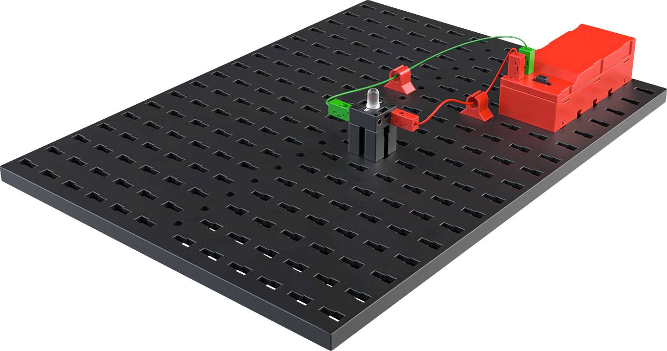 Planche d'expérimentation avec un circuit électrique : batterie, bornes vertes et rouges, câbles et un support noir.