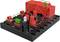 Kit électronique avec circuit : blocs rouges et noirs reliés par des câbles verts, avec une petite LED blanche au centre.