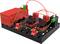 'Circuit électronique avec un boîtier de batterie rouge et des composants noirs, reliés par des fils verts et rouges.'