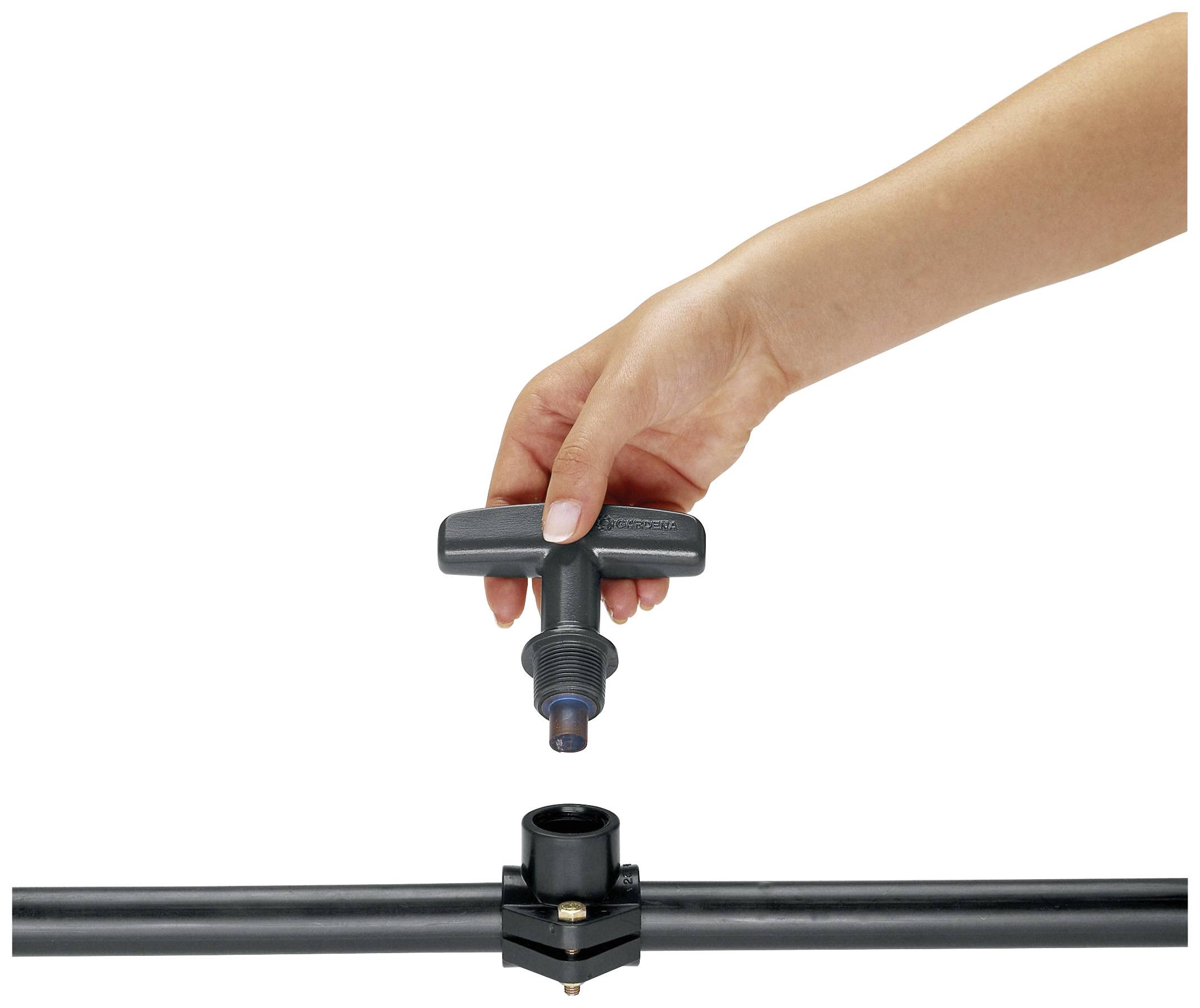 Une main installe un robinet noir sur un tuyau d'eau noir.