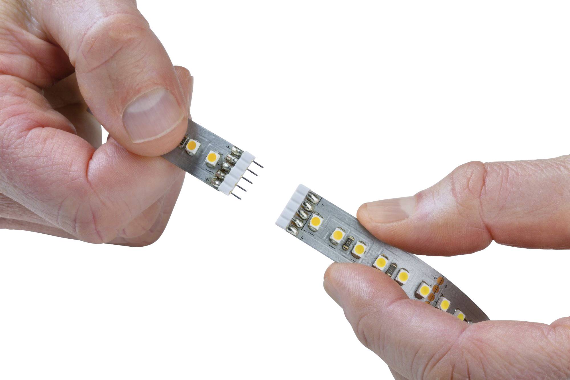 Deux mains tiennent un morceau de bande LED séparé, montrant plusieurs diodes LED jaunes et des connecteurs.