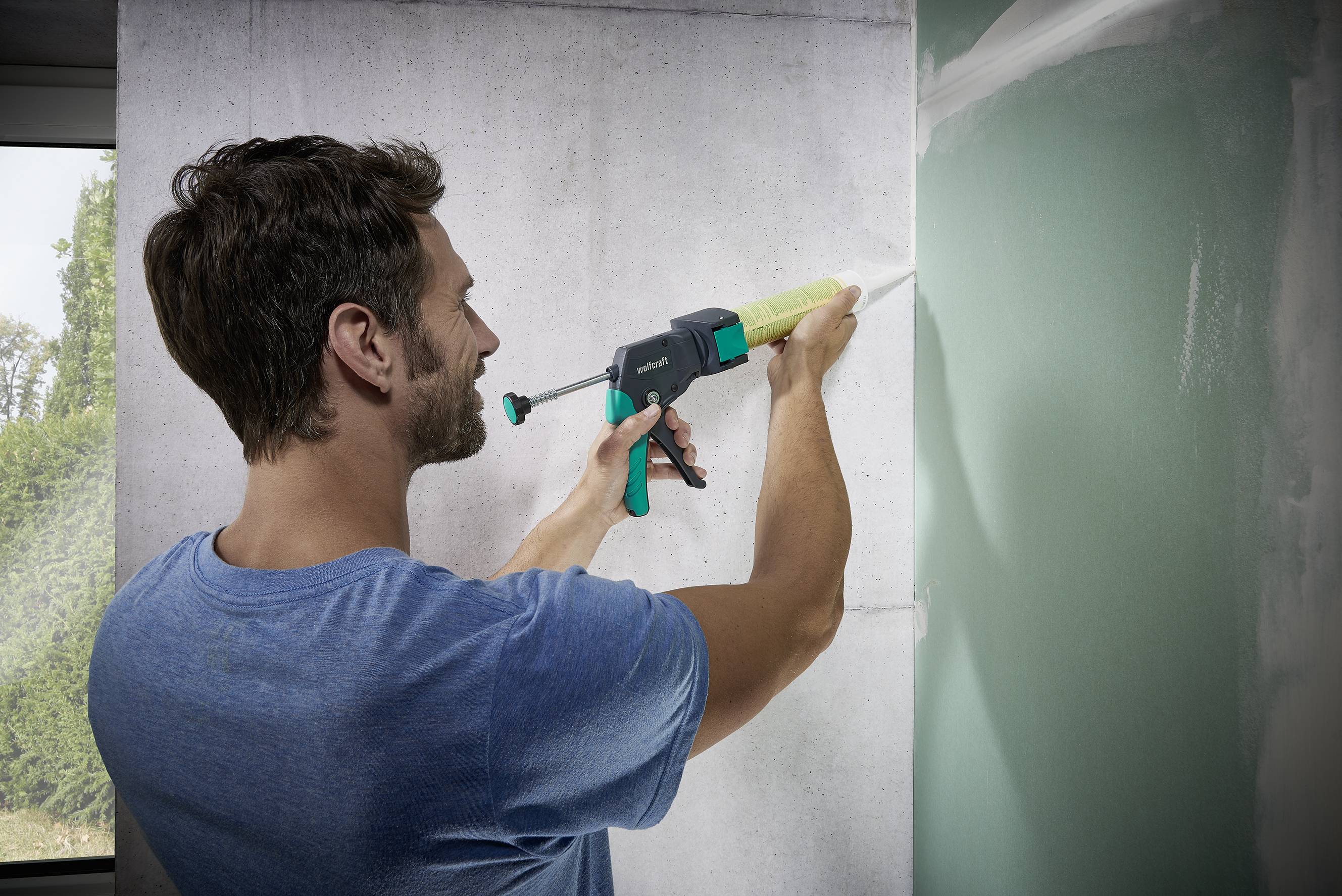 Un homme applique un mastic à l'aide d'un pistolet à cartouche sur un mur, améliorant l'étanchéité de surface.