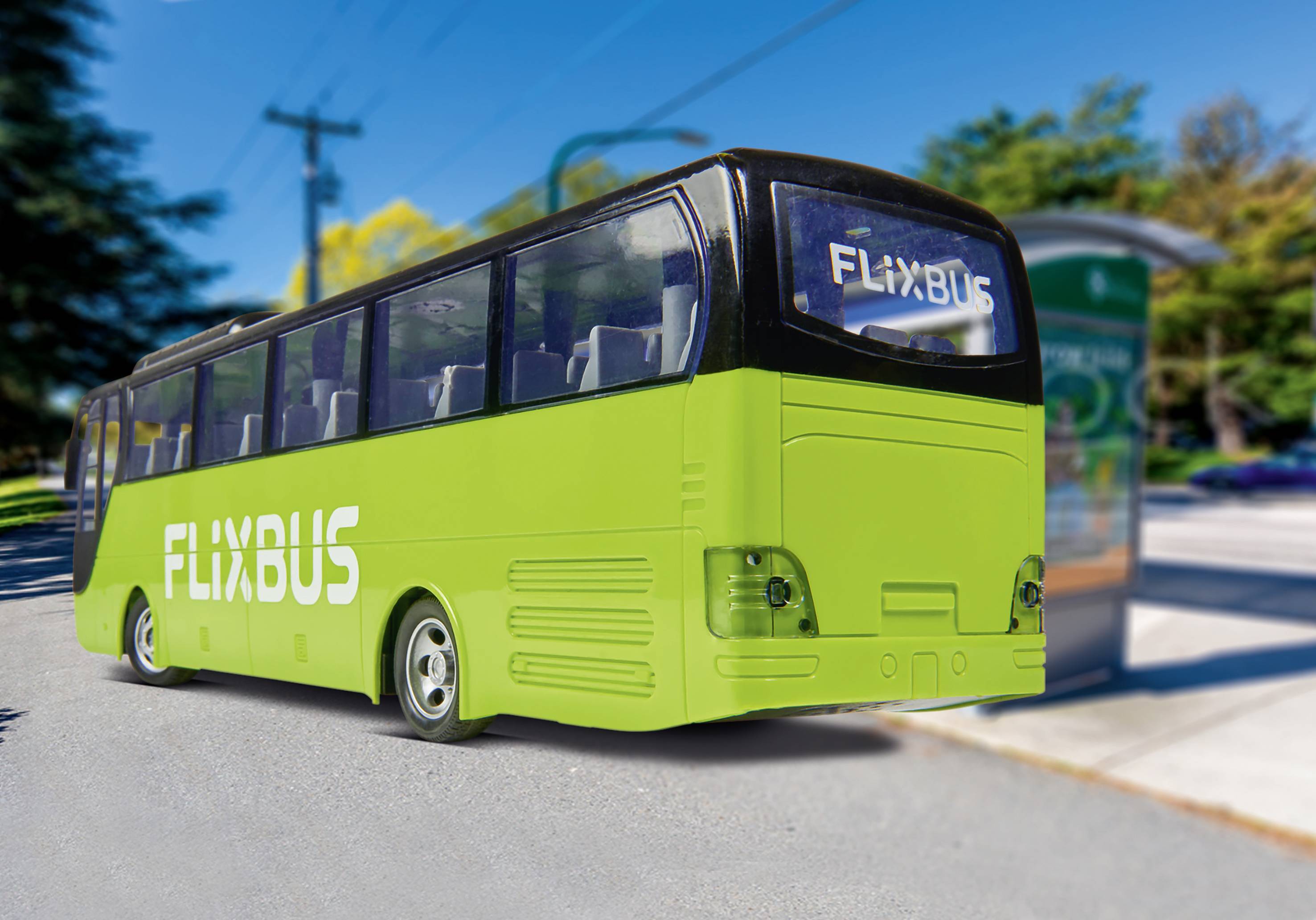 Un bus vert FlixBus est stationné à un arrêt de bus. Des arbres et un ciel ensoleillé sont visibles en arrière-plan.
