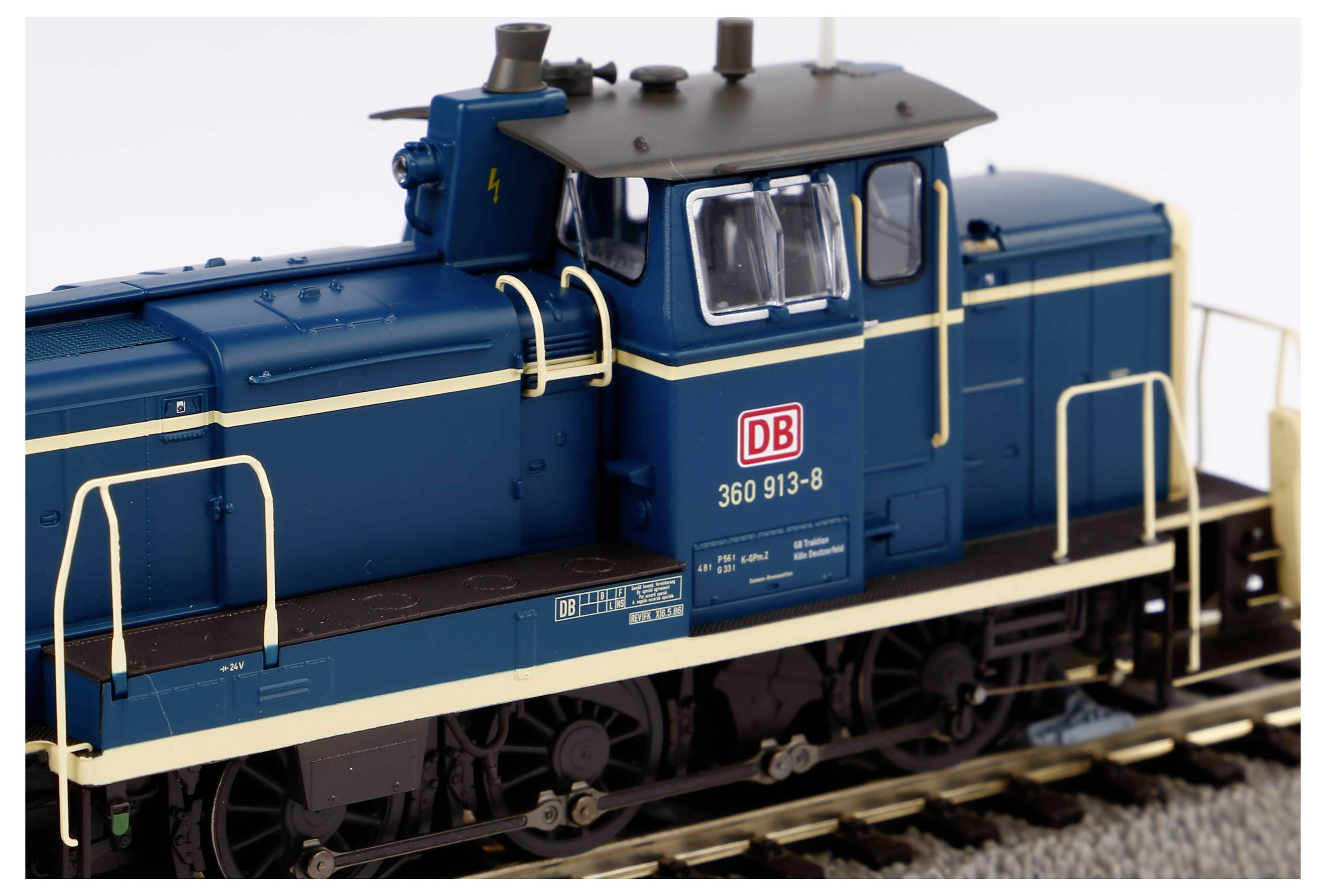 Un modèle bleu d'une locomotive DB sur des rails, avec des garde-corps blancs et un toit gris. Inscription : '360 913-8'.