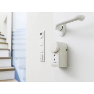 Serrure électronique intelligente sur une porte blanche, avec un escalier en arrière-plan.