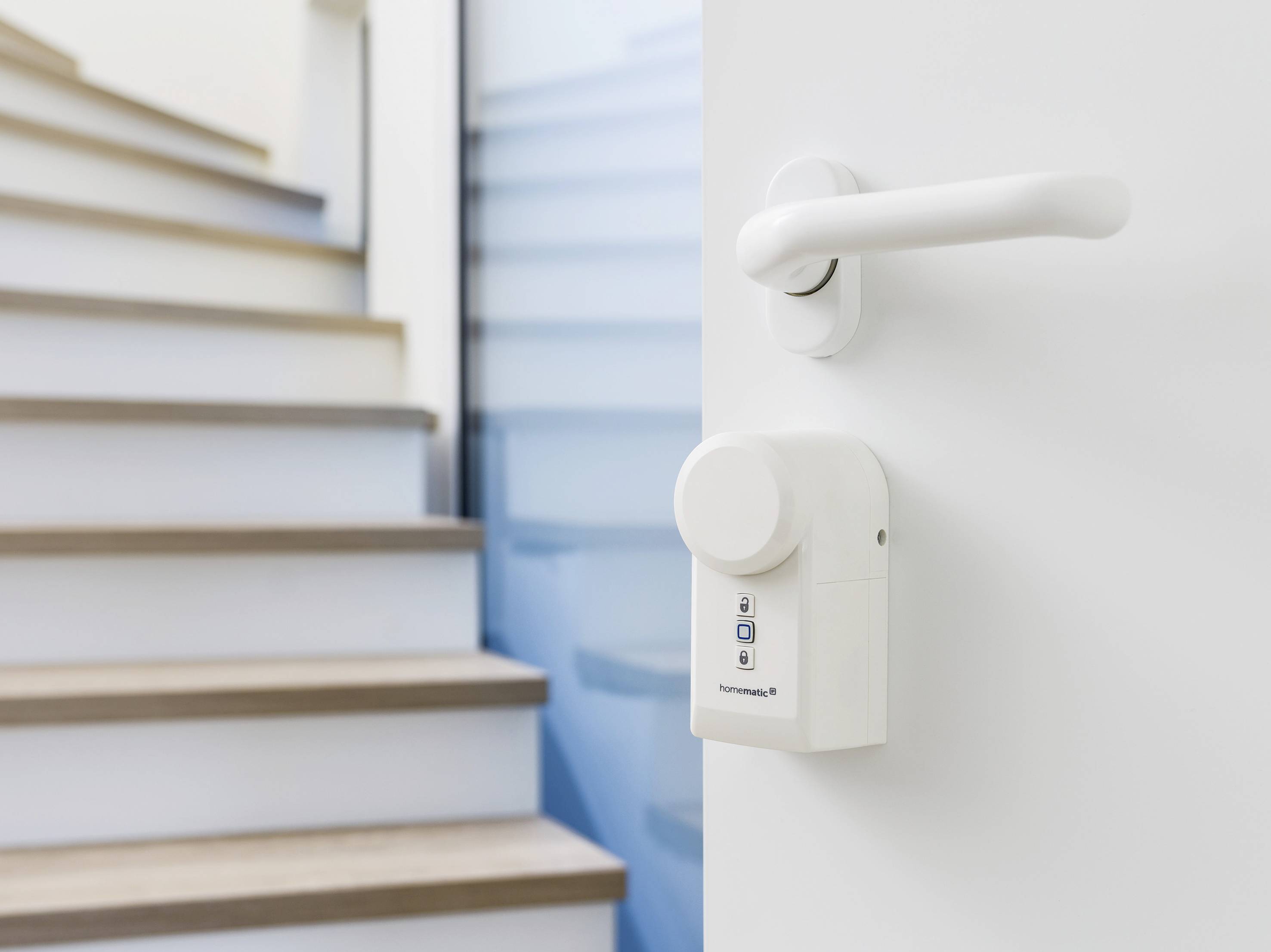 Une porte blanche avec une poignée moderne et une serrure électronique au premier plan, un escalier flou visible en arrière-plan.