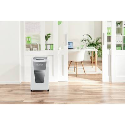 'Bureau avec des sols en bois clair et des étagères blanches, un destructeur de documents au premier plan, un bureau avec un ordinateur portable en arrière-plan.'
