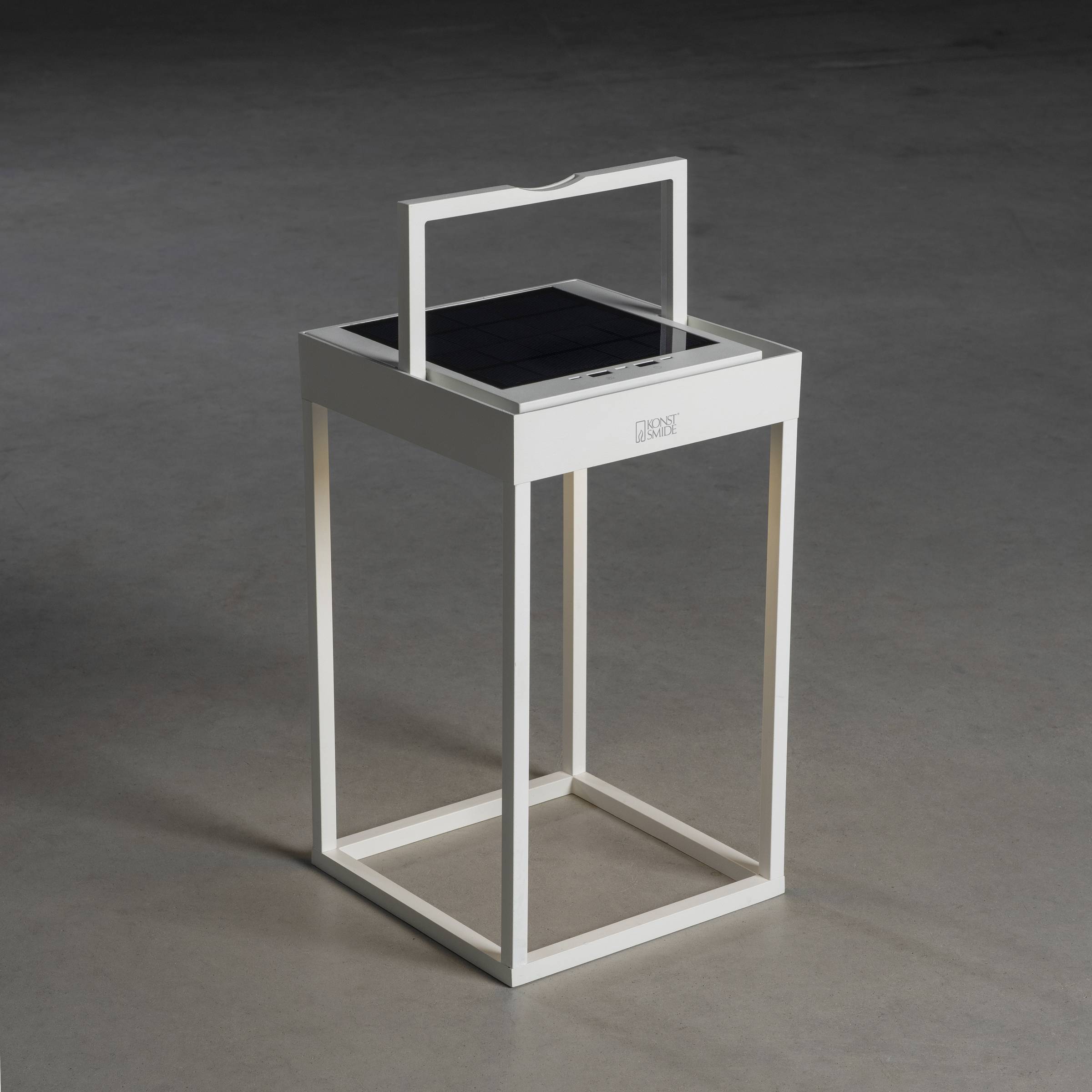Une table d'appoint blanche et moderne avec une surface en verre est posée sur un sol gris. Le design est ouvert et minimaliste.