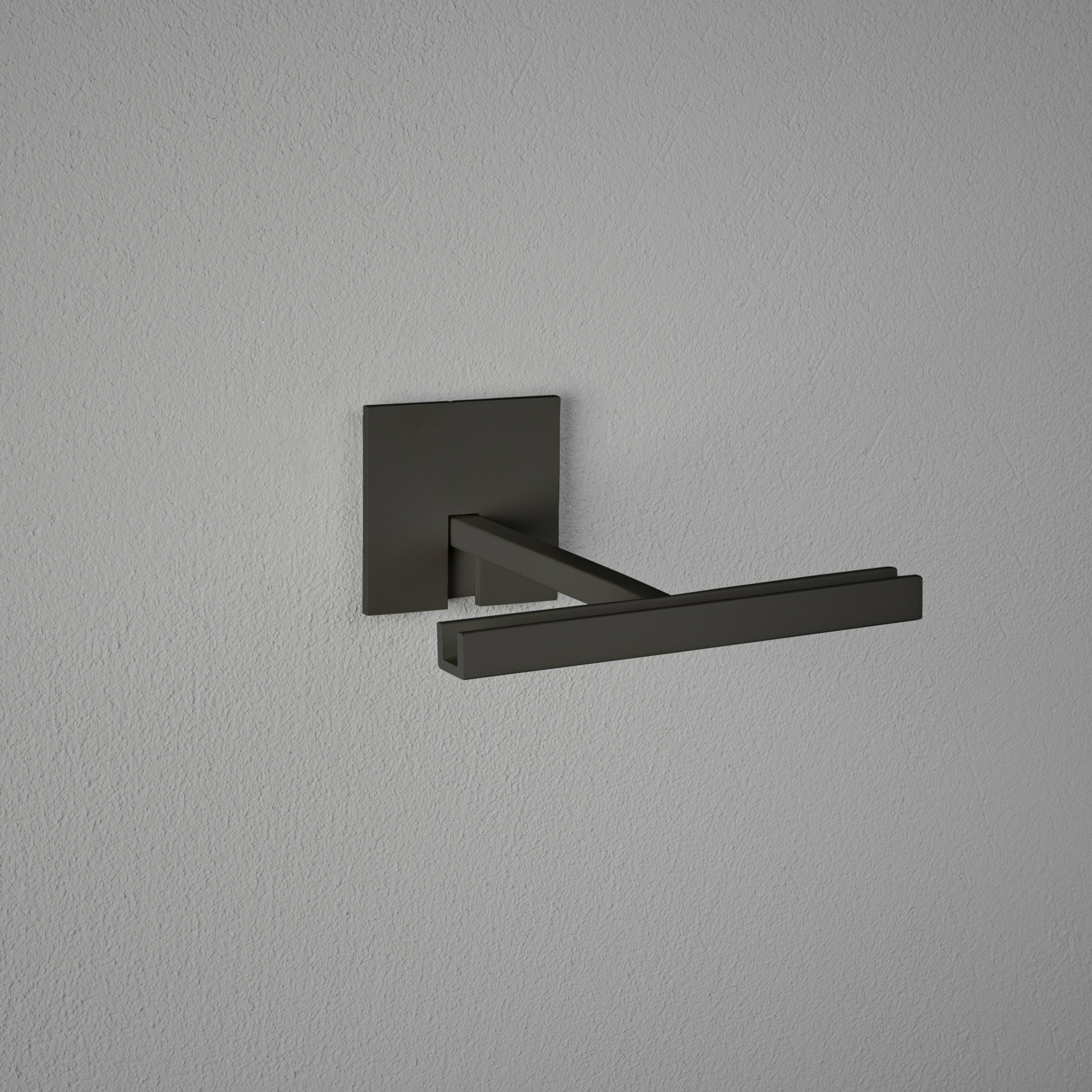 Porte-serviettes noir moderne et individuel, monté sur un mur gris, au design minimaliste.