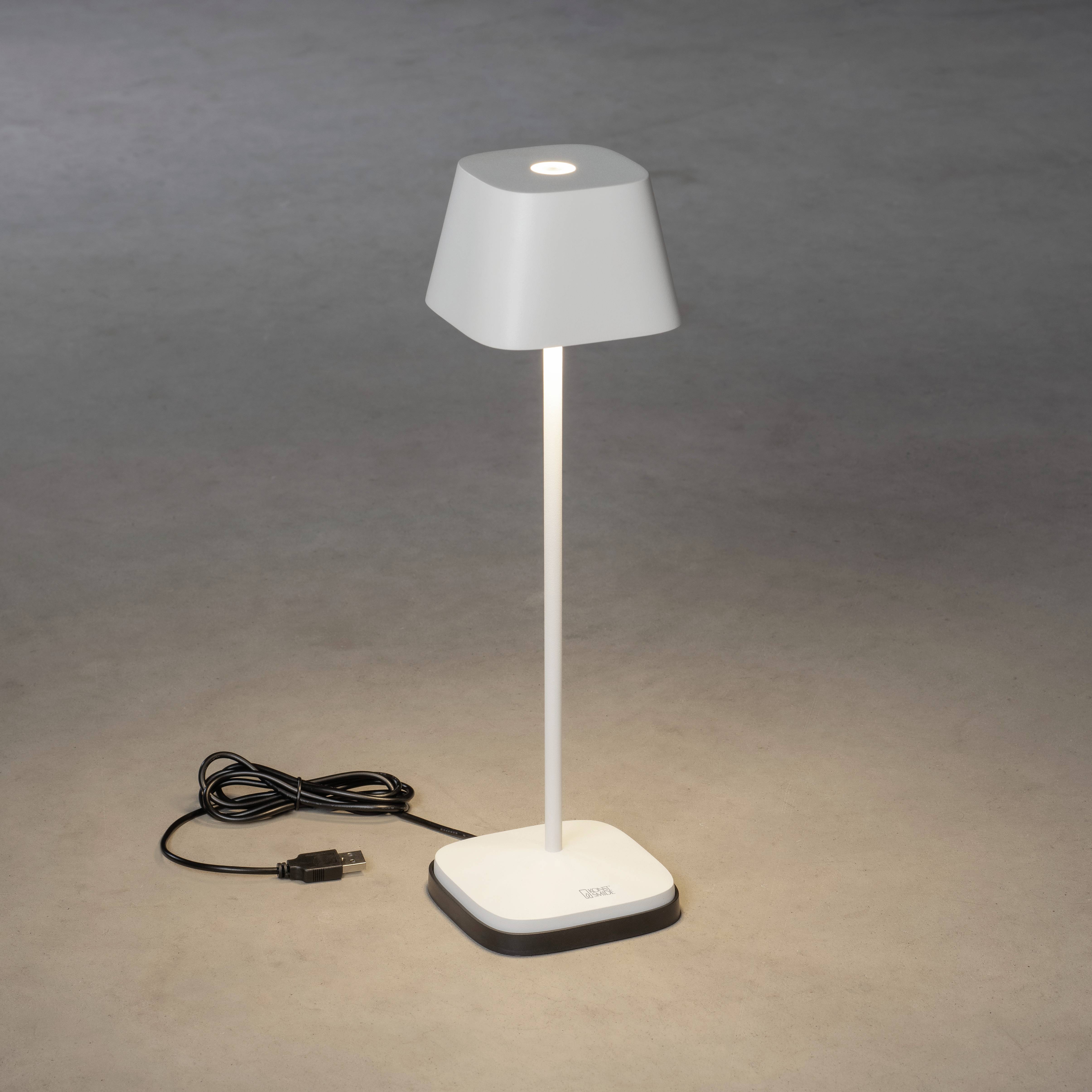 Petite lampe de table blanche et moderne avec un abat-jour carré. La lampe repose sur un socle gris et est équipée d'un câble USB.