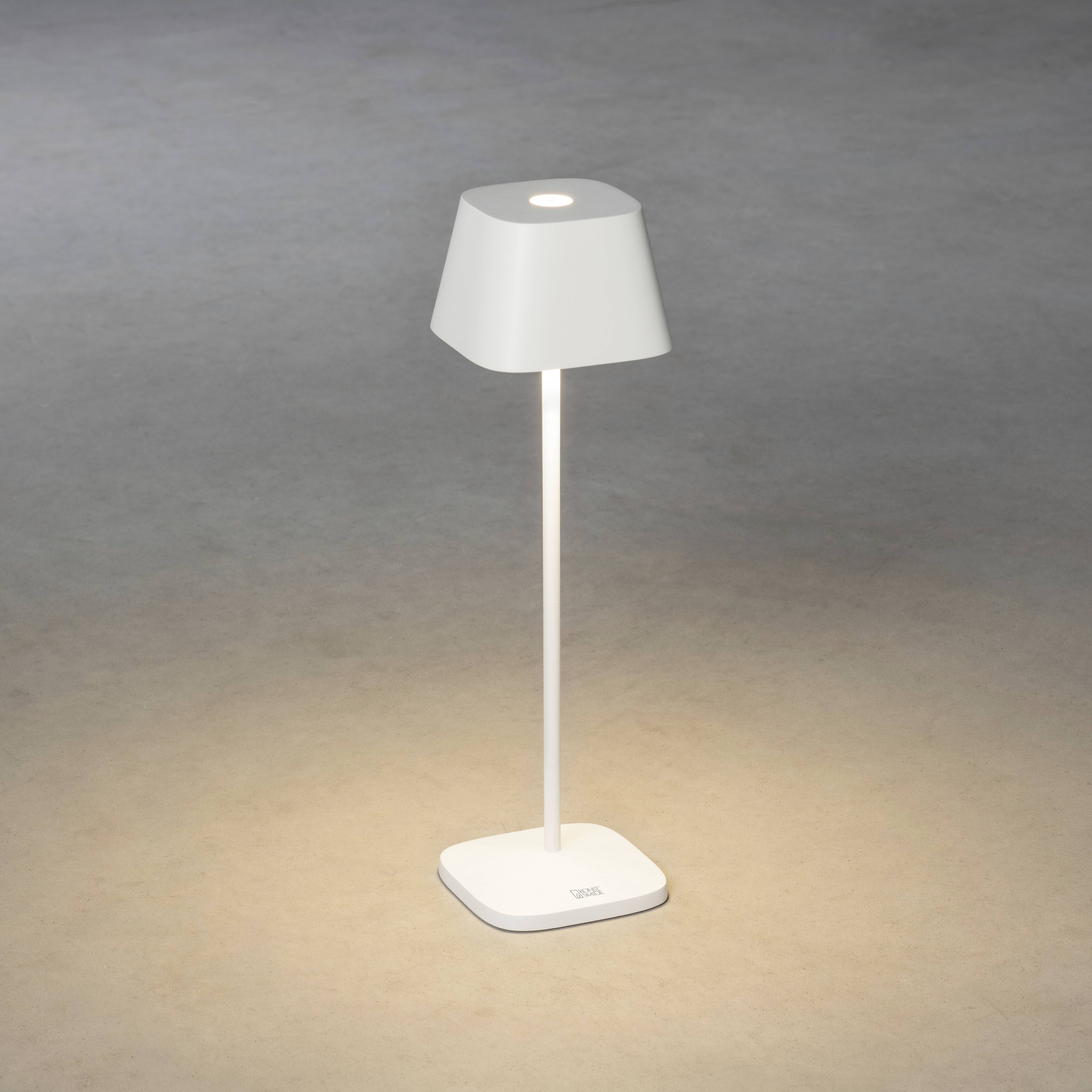 Une lampe sur pied moderne blanche avec un abat-jour carré éclaire sur un sol gris.