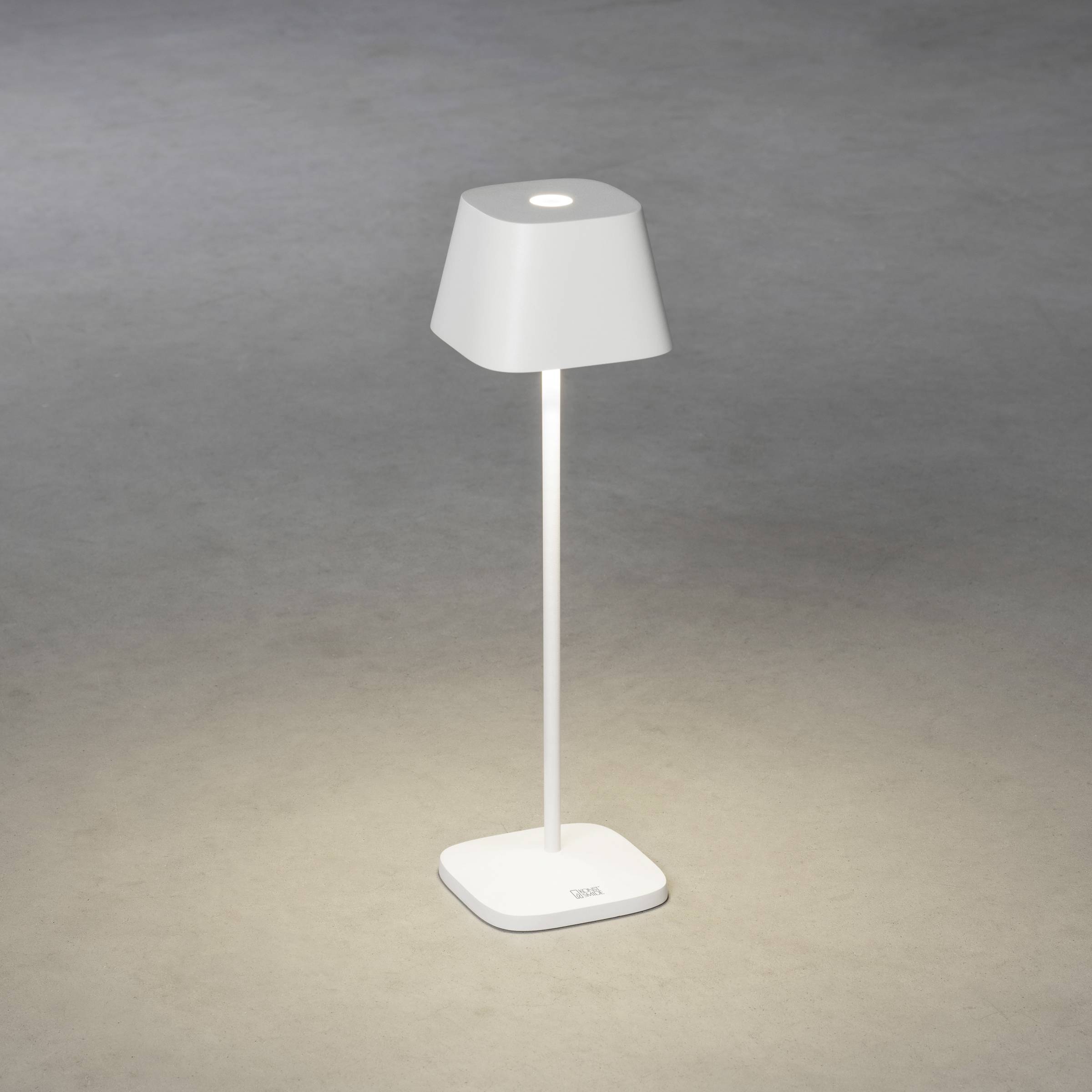 Une lampe sur pied élancée et blanche sur un fond gris, projetant une lumière vers le bas sur sa base. Design moderne et minimaliste.