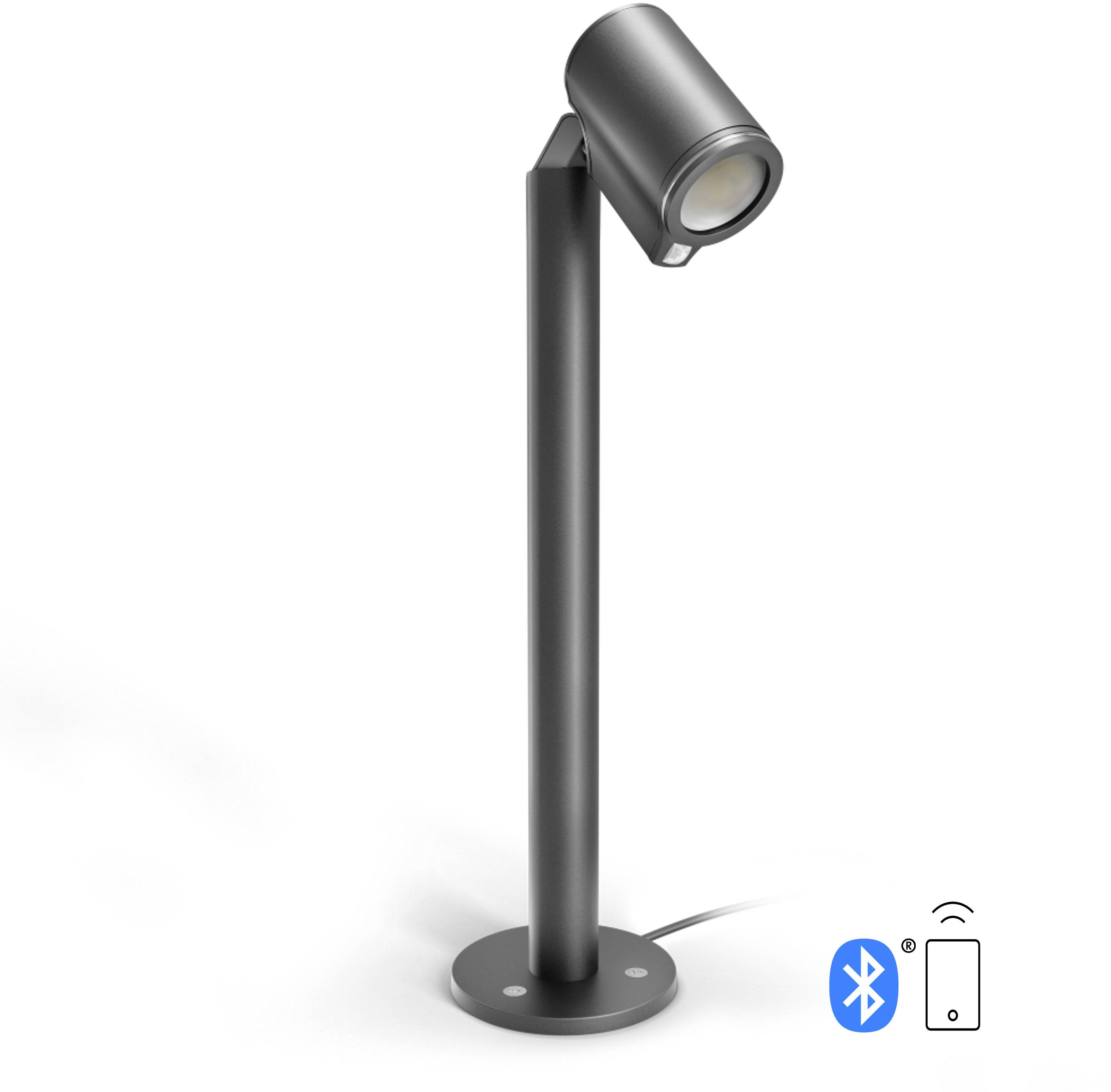 Une lampe d'extérieur noire, cylindrique, montée sur une tige verticale étroite. Symboles Bluetooth et smartphone en bas à droite.