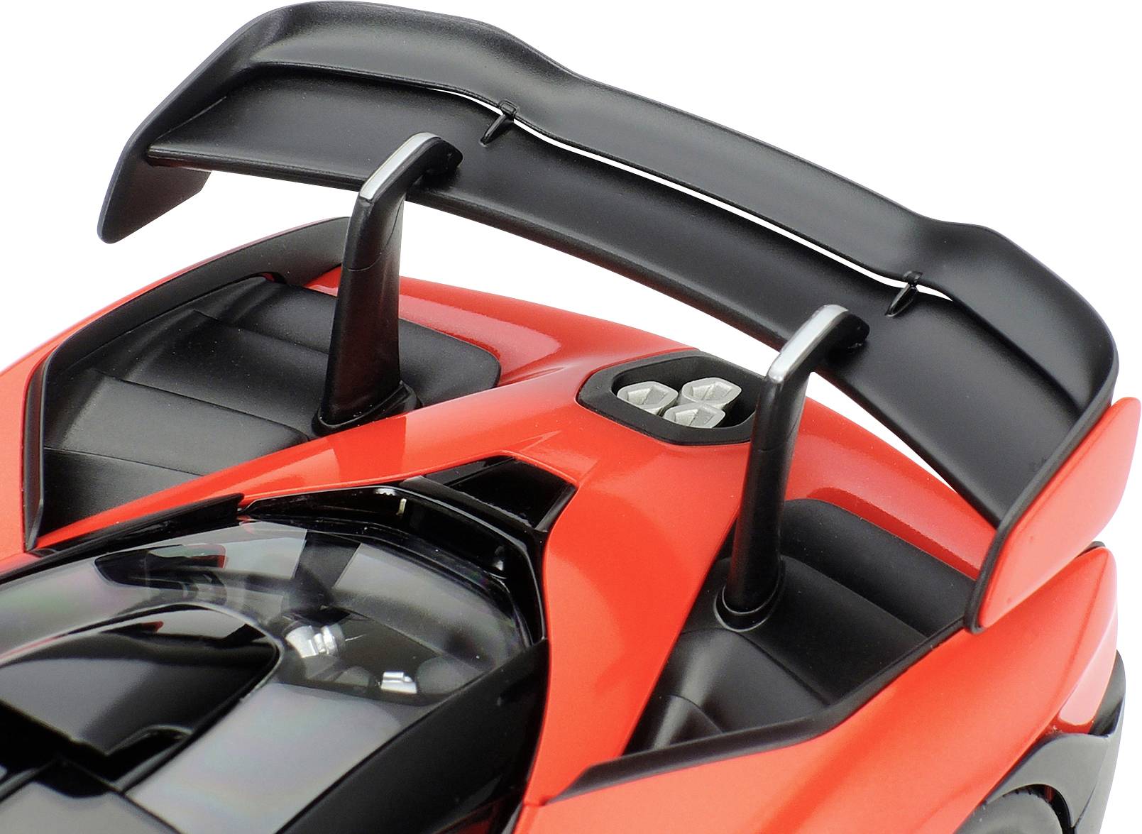 Gros plan sur l'arrière d'une voiture de sport rouge avec un grand aileron courbe et des ouïes d'aération.